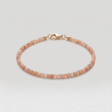 A studio product shot of a women's 2mm natural faceted golden sunstone cube bead bracelet with a 14K gold-filled clasp, highlighting the shimmering peach tones and delicate light-catching facets.