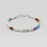 A studio product shot of a 4mm mixed gemstone heishi bracelet featuring white turquoise, tiger's eye, and amethyst, with sterling silver flat rondel beads for a refined, colorful aesthetic.
