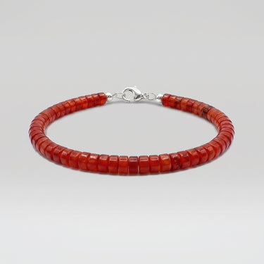 A studio product shot of a women's 4mm natural red agate heishi bead bracelet with a sterling silver clasp, highlighting the vibrant crimson tones and uniform disk-shaped stones.