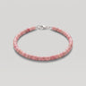 A pink beaded heishi bracelet made of small pink rhodonite cylindrical stone beads with a silver lobster clasp, shown on a neutral light gray background.