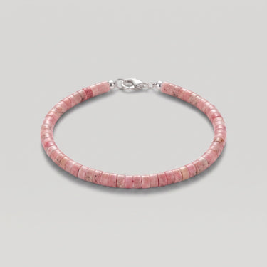 A pink beaded heishi bracelet made of small pink rhodonite cylindrical stone beads with a silver lobster clasp, shown on a neutral light gray background.