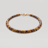 A studio product shot of a women's 4mm natural tiger's eye heishi bead bracelet with a 14K gold-filled clasp, highlighting the rich golden-brown chatoyancy and disk shape.