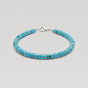 A studio product shot of a 4mm turquoise heishi bead bracelet with a sterling silver lobster clasp, showcasing the uniform disk shape and natural semi-precious stone texture.
