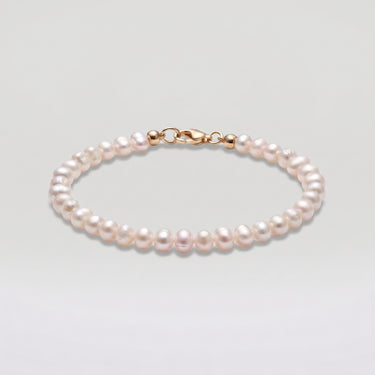 A studio hero shot of a 4-5mm natural white baroque freshwater pearl bracelet, showcasing the unique organic shapes and luminous luster of the dainty pearls.