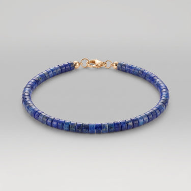 A studio product shot of a women's 2-3mm natural faceted lapis lazuli cube bead bracelet with a sterling silver lobster clasp, highlighting the deep royal blue gemstone tones and light-catching geometric facets.