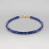 A studio product shot of a women's 4mm natural lapis lazuli heishi bead bracelet with a 14K gold-filled clasp, highlighting the deep royal blue gemstone tones and sleek disk shape.