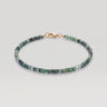 A studio product shot of a women's 3mm natural faceted tourmaline cube bead bracelet with a 14K gold-filled clasp, highlighting the multi-tonal deep green and earthy gemstone hues.