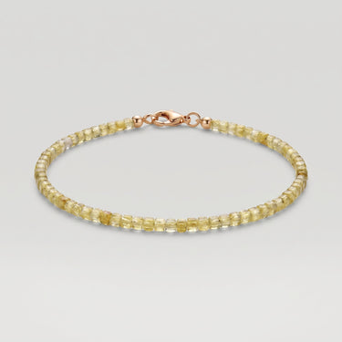 A studio product shot of a women's delicate 2mm natural faceted peridot cube bead bracelet with a 14K gold-filled clasp.