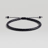 A black beaded bracelet with a sliding knot closure, shown on a neutral light gray background.
