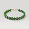 A studio product shot of a women's 8mm natural green jade bead bracelet with a 14k gold-filled lobster clasp.  