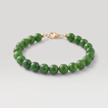 A studio product shot of a women's 8mm natural green jade bead bracelet with a 14k gold-filled lobster clasp.  
