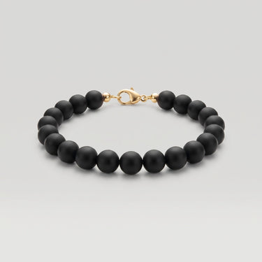 A studio product shot of a women's 8mm natural matte onyx bead bracelet with a 14K gold-filled lobster clasp.