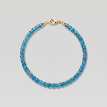 A studio product shot of a women's AAA natural teal blue apatite faceted 2-3mm cube beads bracelet with 14k gold-filled lobster clasp.
