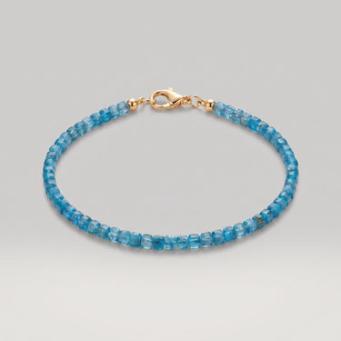 A studio product shot of a women's AAA natural teal blue apatite faceted 2-3mm cube beads bracelet with 14k gold-filled lobster clasp on a white background.