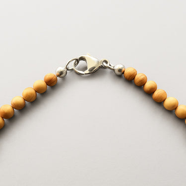 Close-up shot of the sterling silver clasp for a 4mm round golden tan color sandalwood bead necklace against a neutral background