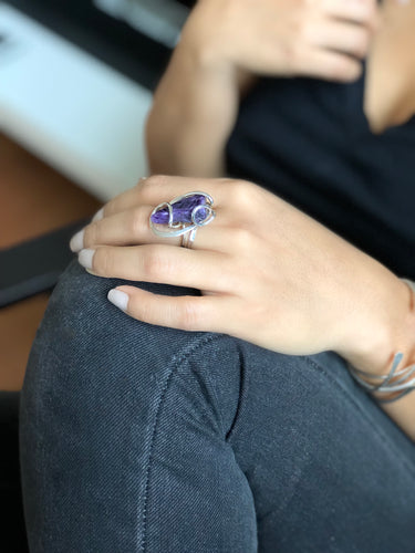 Side view of the floating wave setting, showing the sterling silver wire loops and the adjustable ring band on model's hand.
