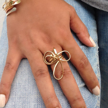 Close-up of model wearing a sculptural 14k gold-filled statement ring featuring an abstract wire-formed wave design