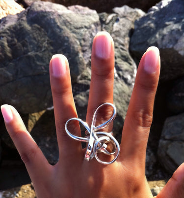 model wearing a sculptural sterling silver statement ring featuring an abstract wire-formed wave design