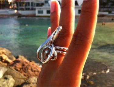 side view of model wearing a sculptural sterling silver statement ring featuring an abstract wire-formed wave design