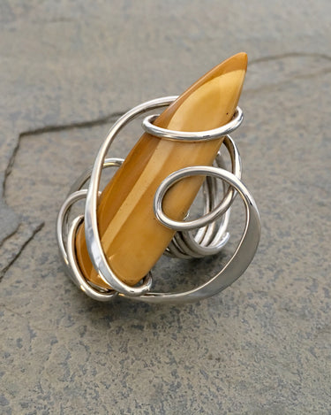 Close-up of yellow jasper stone wrapped in sterling silver wire forming sculptural ring design