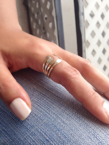 Close-up of four stackable minimalist open-end rings for women, showing hammered texture and hand-flattened tips.