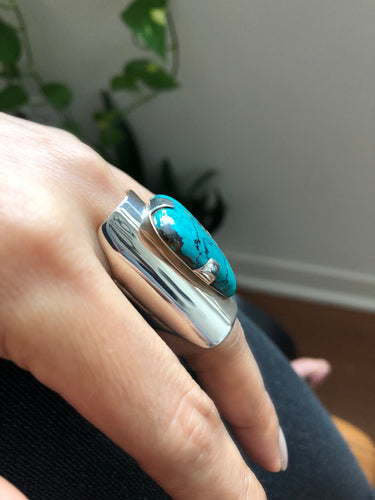 Large turquoise ring with bold silver design shown on hand
