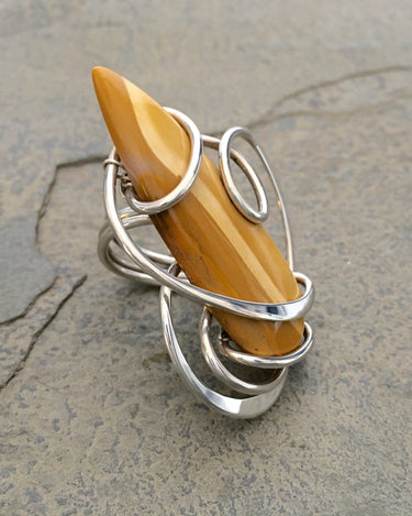 Side view of yellow jasper stone wrapped in sterling silver wire forming sculptural ring design